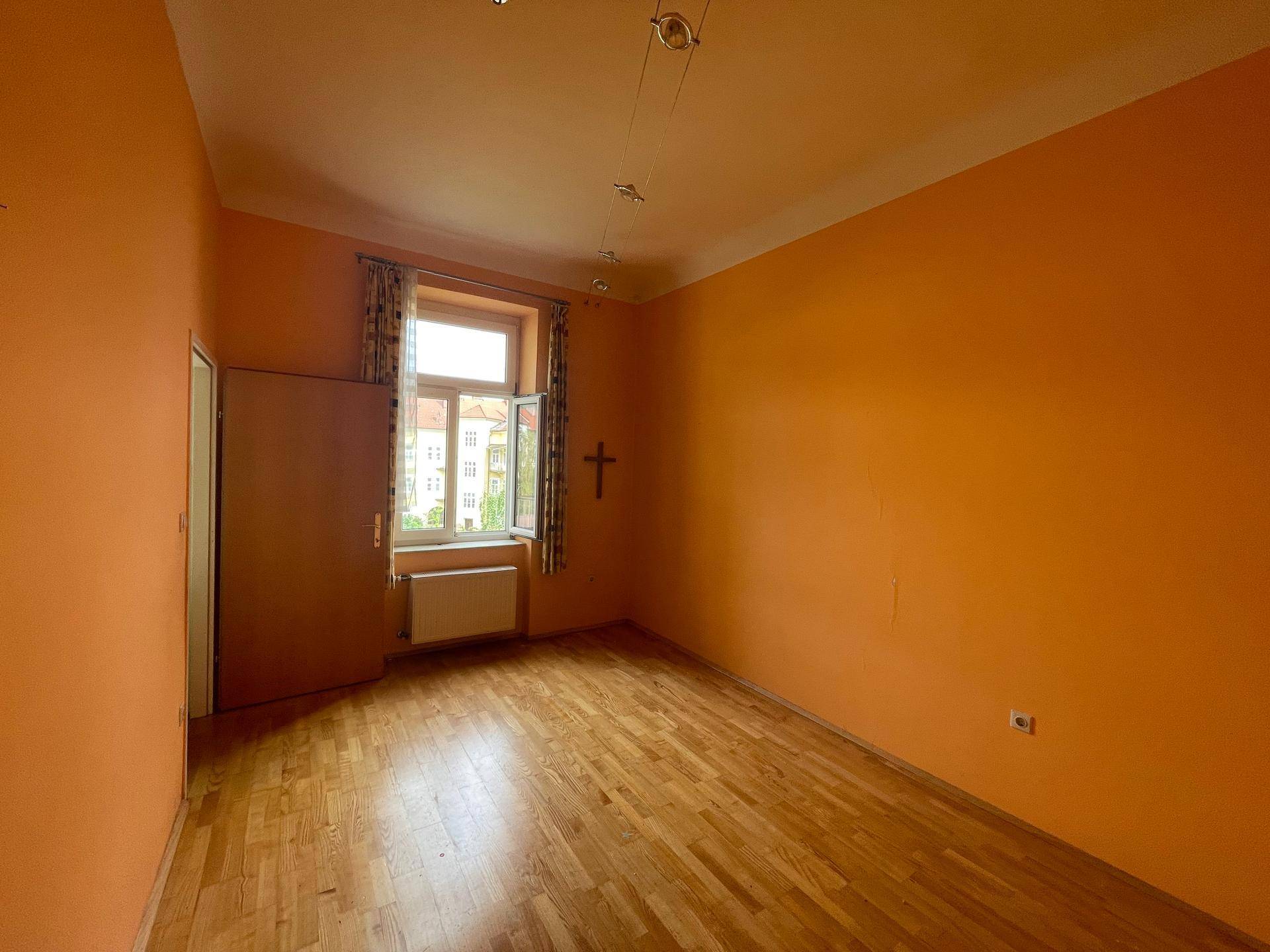 Gemütliches Zimmer mit orangefarbenen Wänden und Holzboden, mit Blick nach draußen.