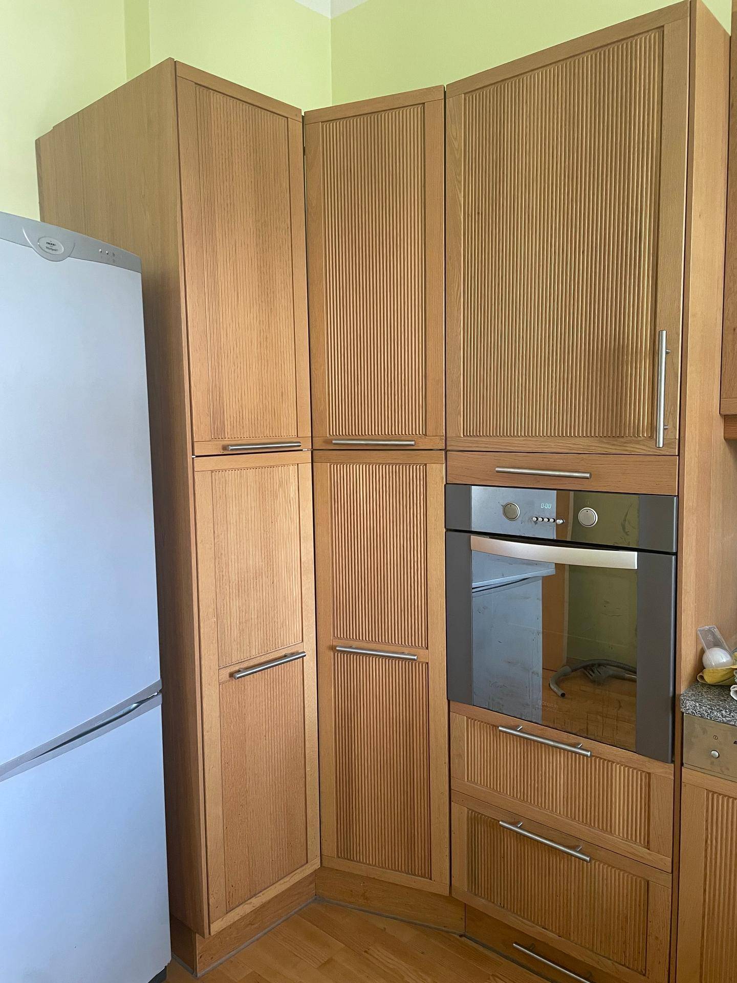 Detailansicht der Holzküche mit integriertem Backofen und Kühlschrank, sowie viel Stauraum.