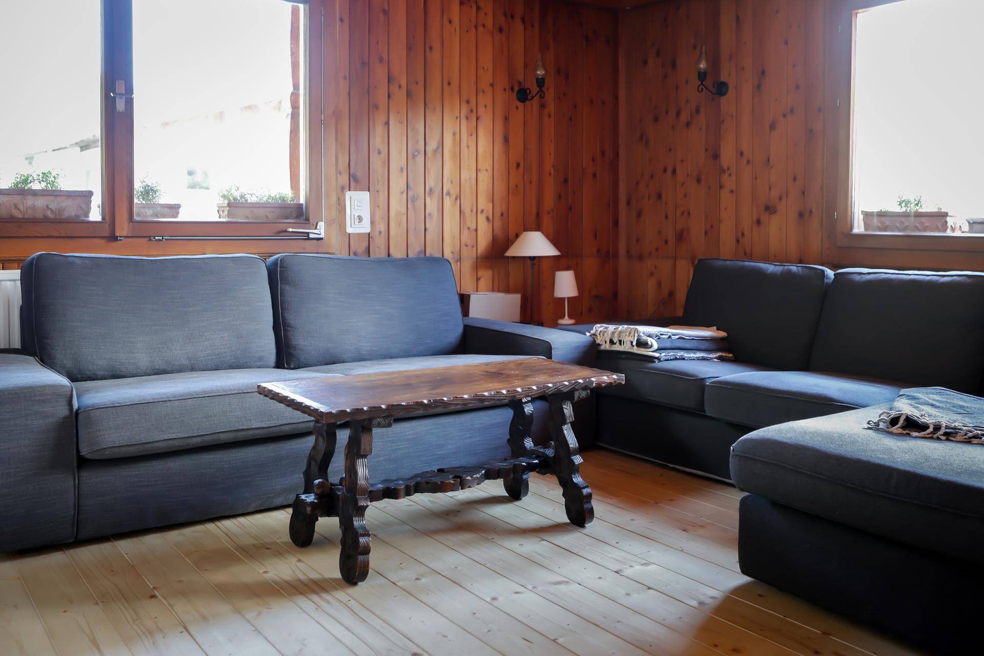 Gemütliches Wohnzimmer im alpinen Stil mit Holzvertäfelung und bequemen Sofas.