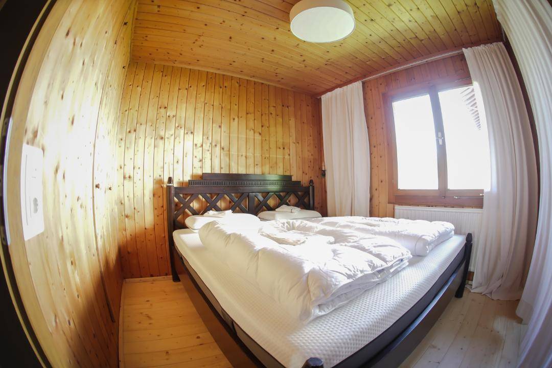 Schlafzimmer mit Holzvertäfelung, Holzboden und einem Doppelbett mit weißer Bettwäsche.