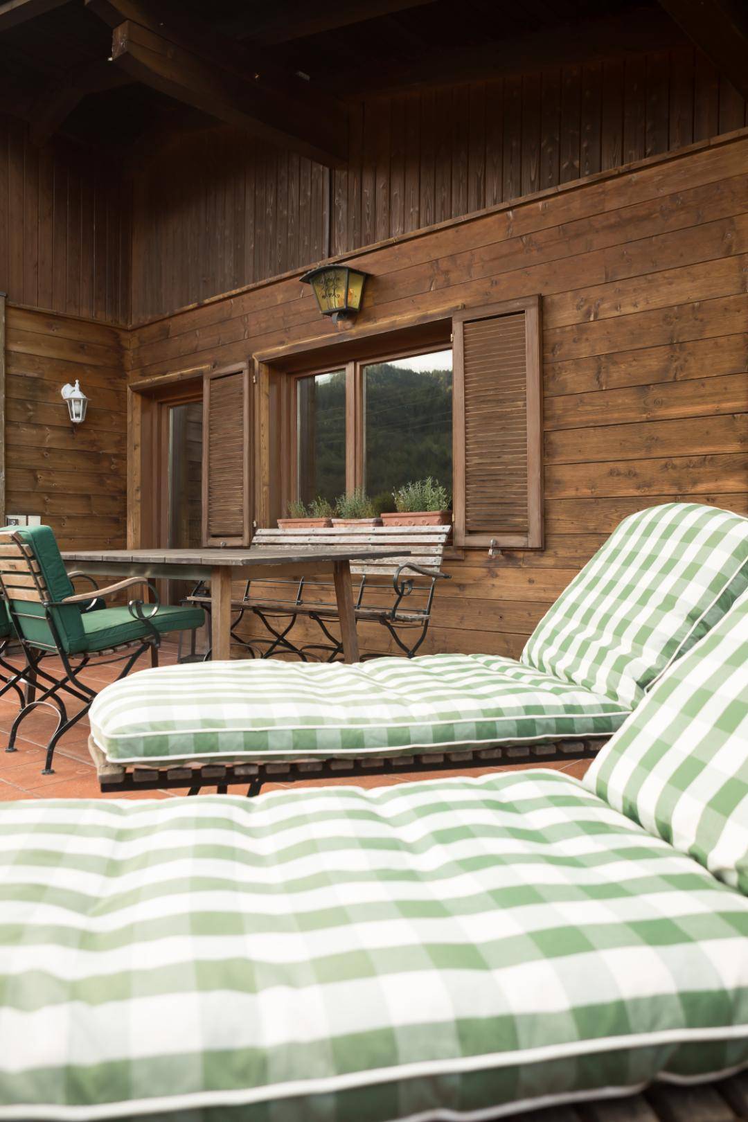 Detailansicht der Terrasse mit Liegestühlen und Blick auf die grüne Umgebung.