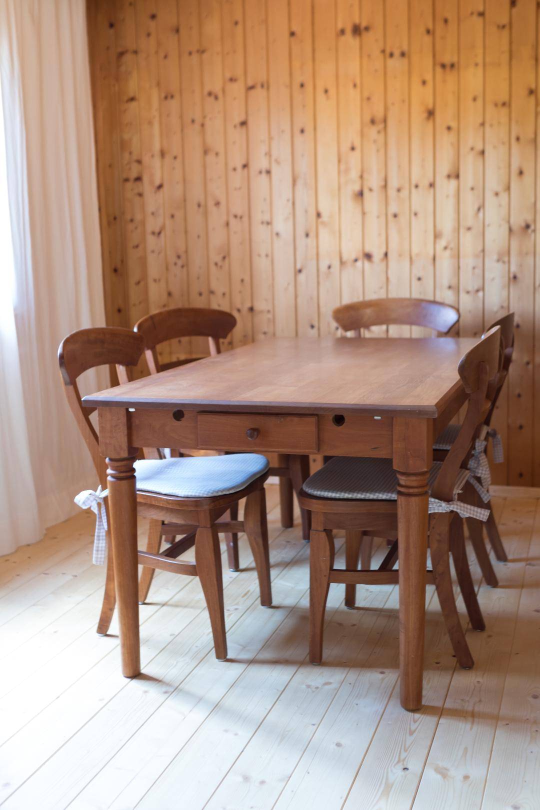 Esszimmer mit Holztisch und Stühlen im traditionellen Stil, umgeben von Holzvertäfelung.