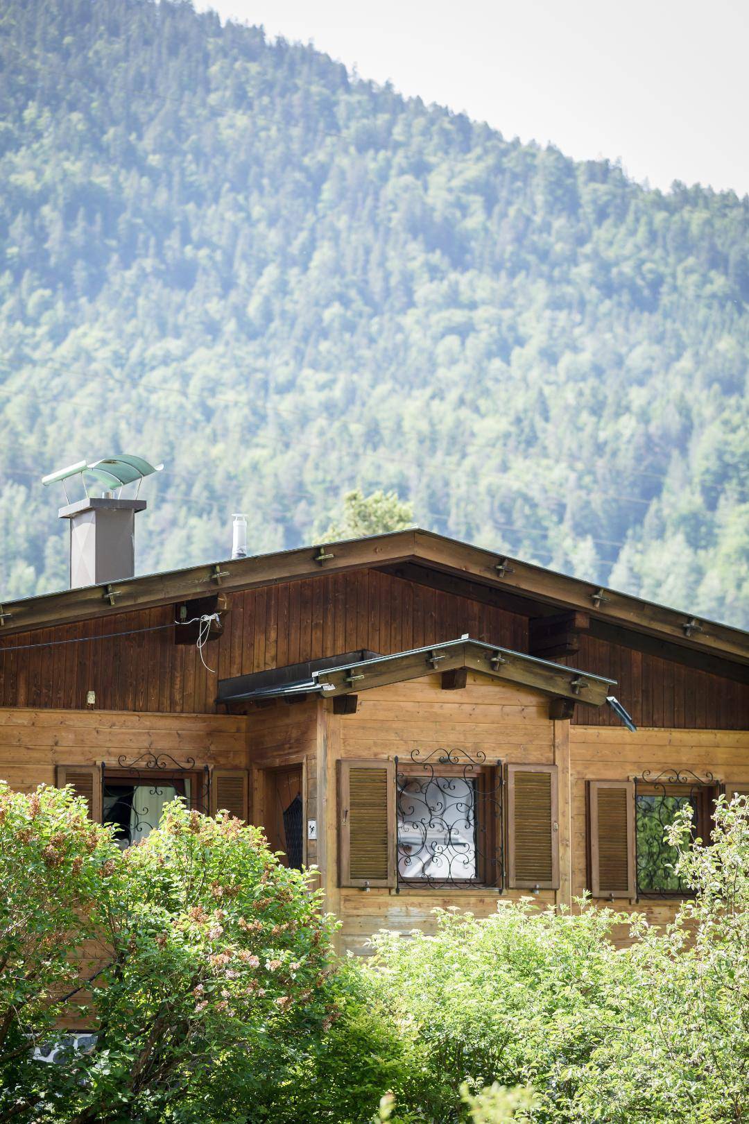 Traditionelles Holzhaus in den Bergen mit grüner Umgebung und Bergblick.