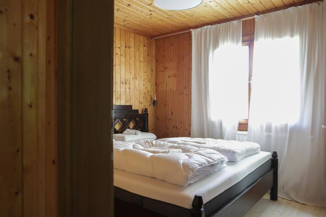 Gemütliches Schlafzimmer mit Holzvertäfelung, Doppelbett und viel Tageslicht.