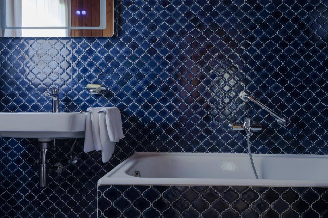 Modernes Badezimmer mit blauen Mosaikfliesen, Waschbecken und Badewanne.