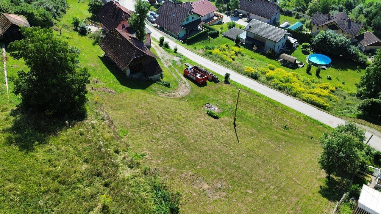 Weitläufiges Grundstück mit Straße, Häusern in der Ferne und einem Pool in grüner Umgebung.