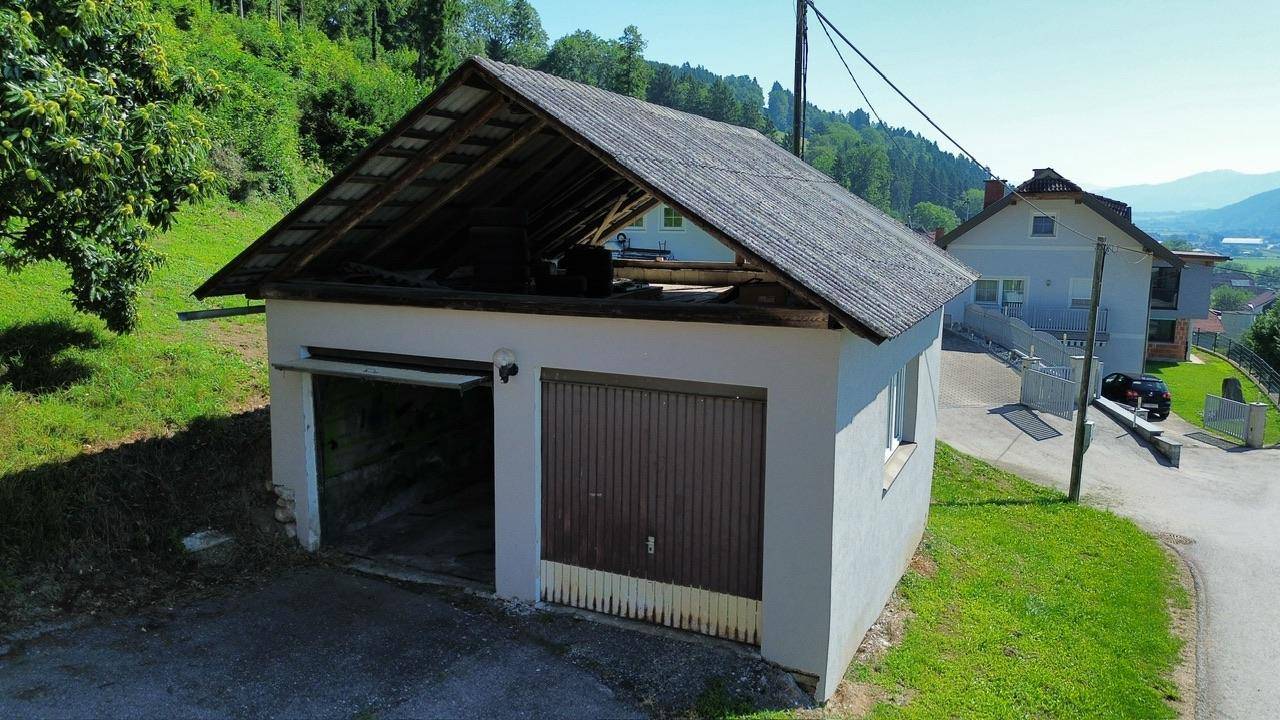 Freistehende Doppelgarage mit offenem Dachstuhl und zwei Einfahrten in ländlicher Umgebung.