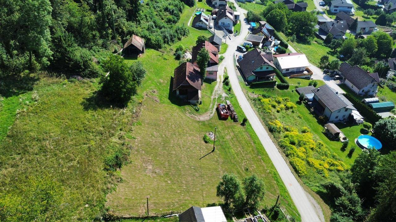 Ländliche Gegend mit Häusern, Feldern und einer kurvenreichen Straße, umgeben von Wald.