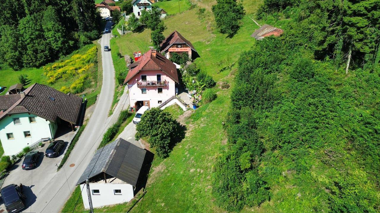 Ländliche Siedlung mit Häusern und Straßen, eingebettet in eine weite grüne Hügellandschaft.