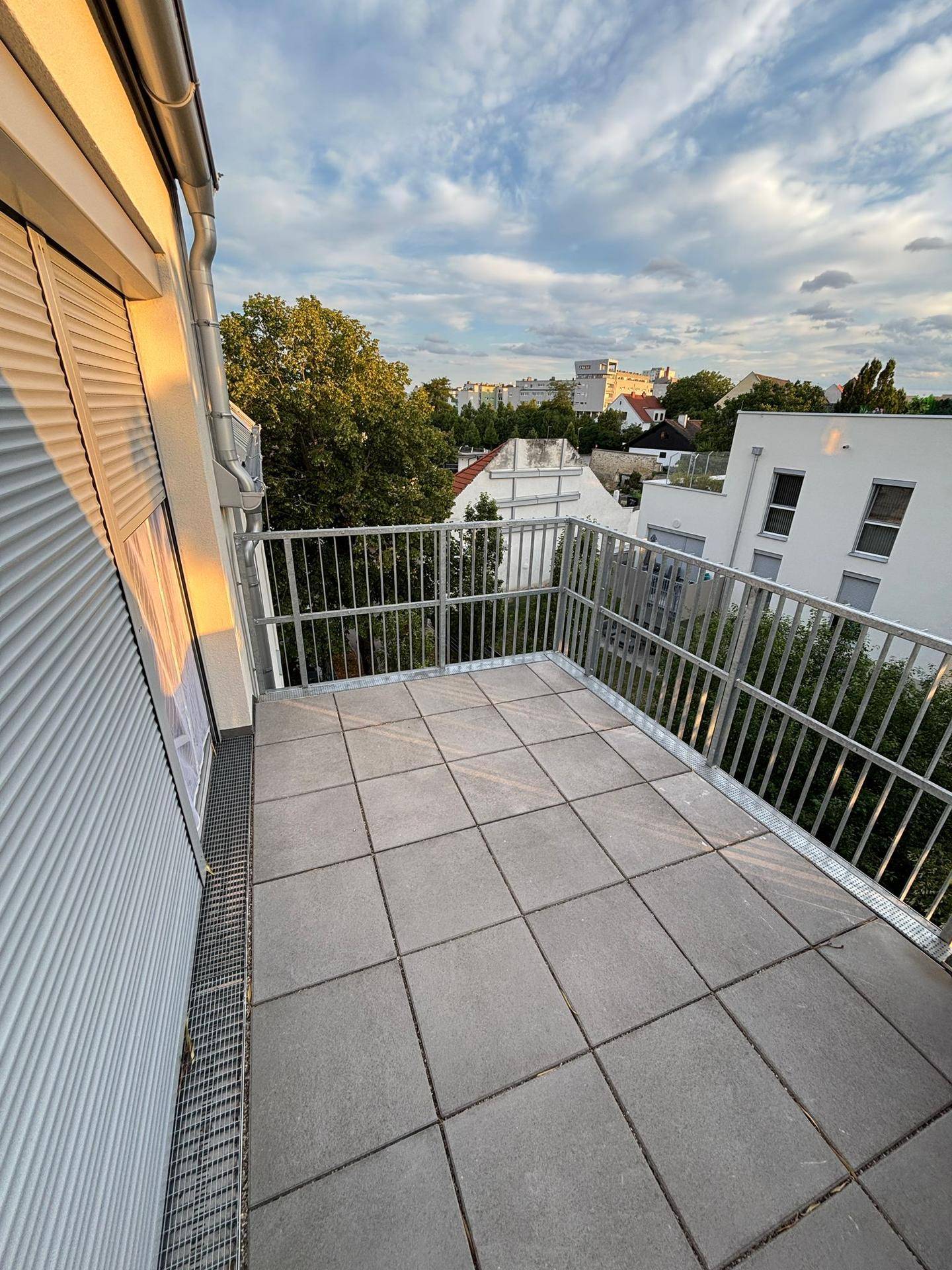 Geräumiger Balkon mit Fliesenboden und Blick auf die umliegende Wohngegend.