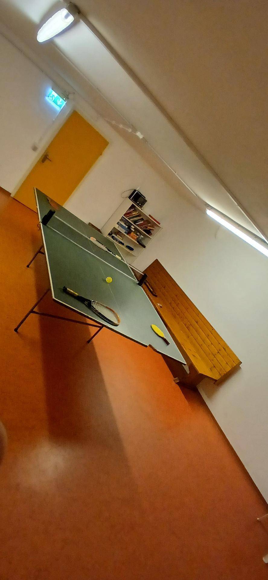 Geräumiger Spielraum mit Tischtennisplatte und orangefarbenem Bodenbelag, ideal für Freizeitaktivitäten.