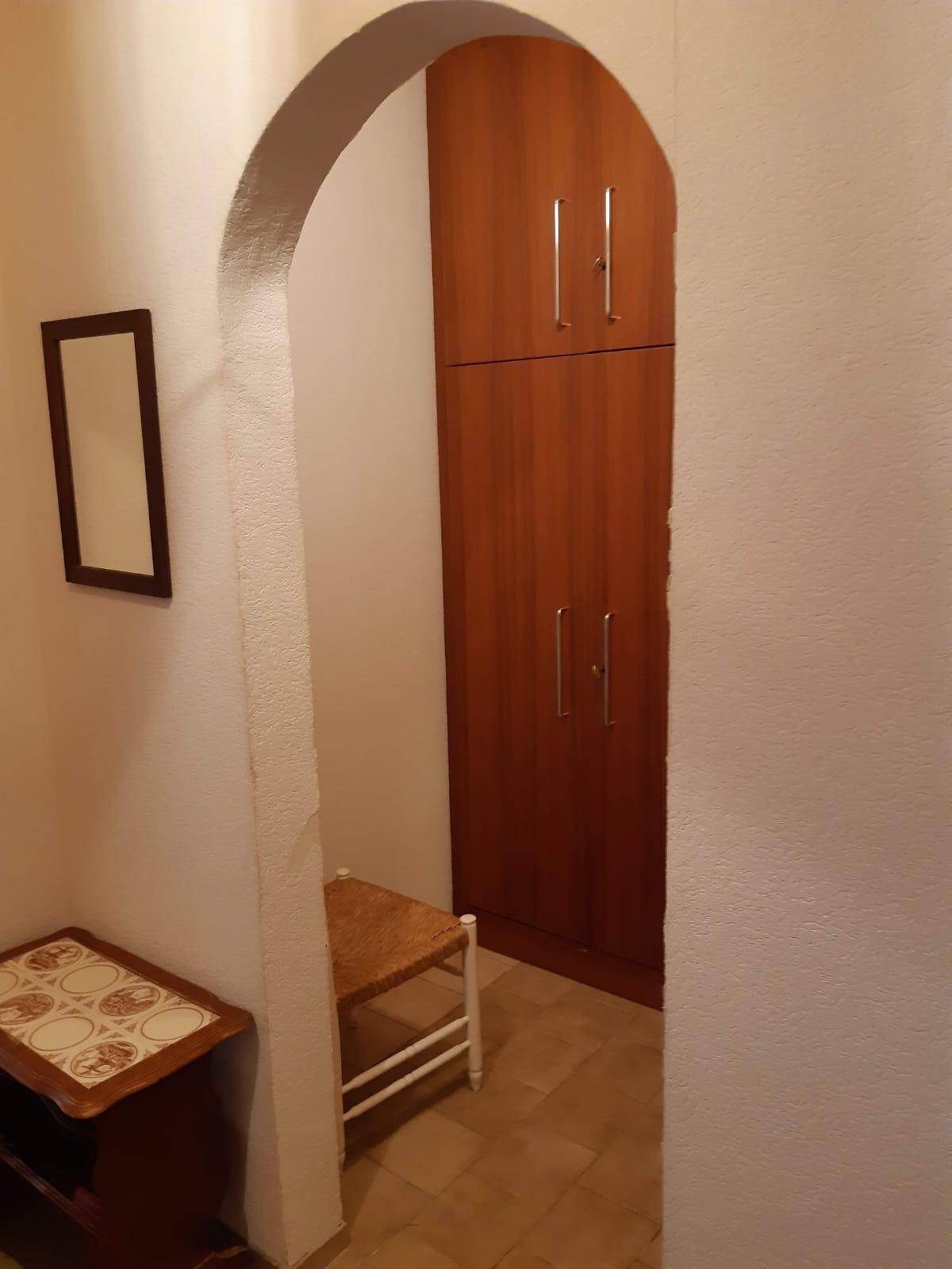 Eingangsbereich mit Rundbogen, integriertem Holzschrank und einem kleinen Spiegel.