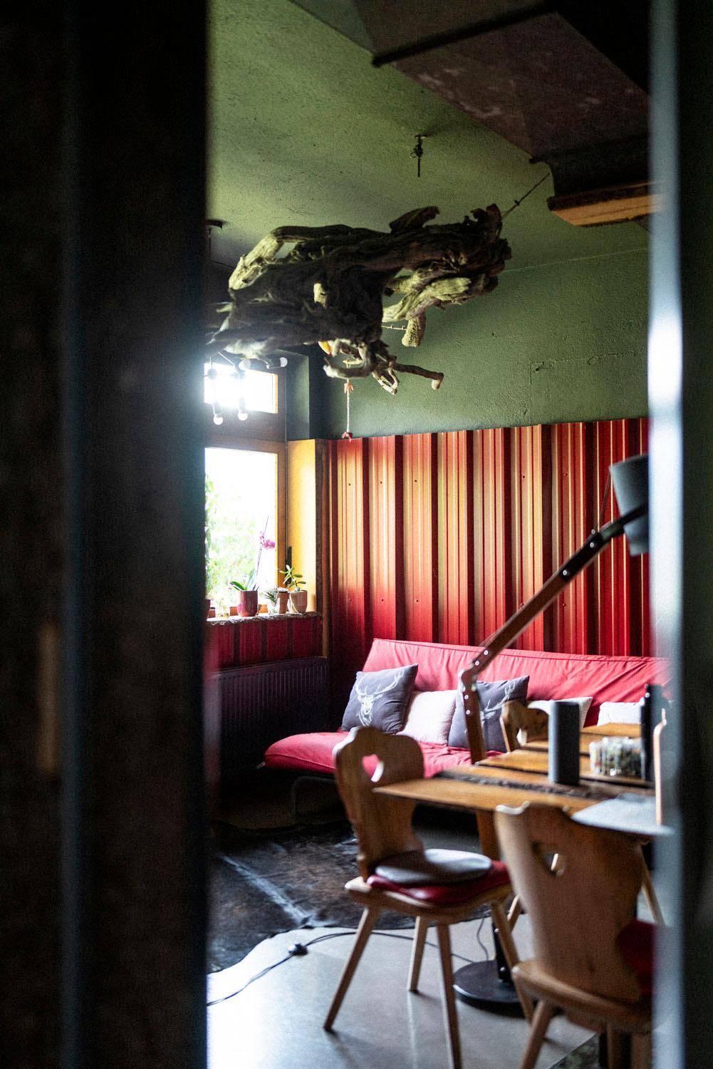 Gemütlicher Wohnbereich mit rotem Sofa, Holztisch und dekorativer Deckeninstallation.