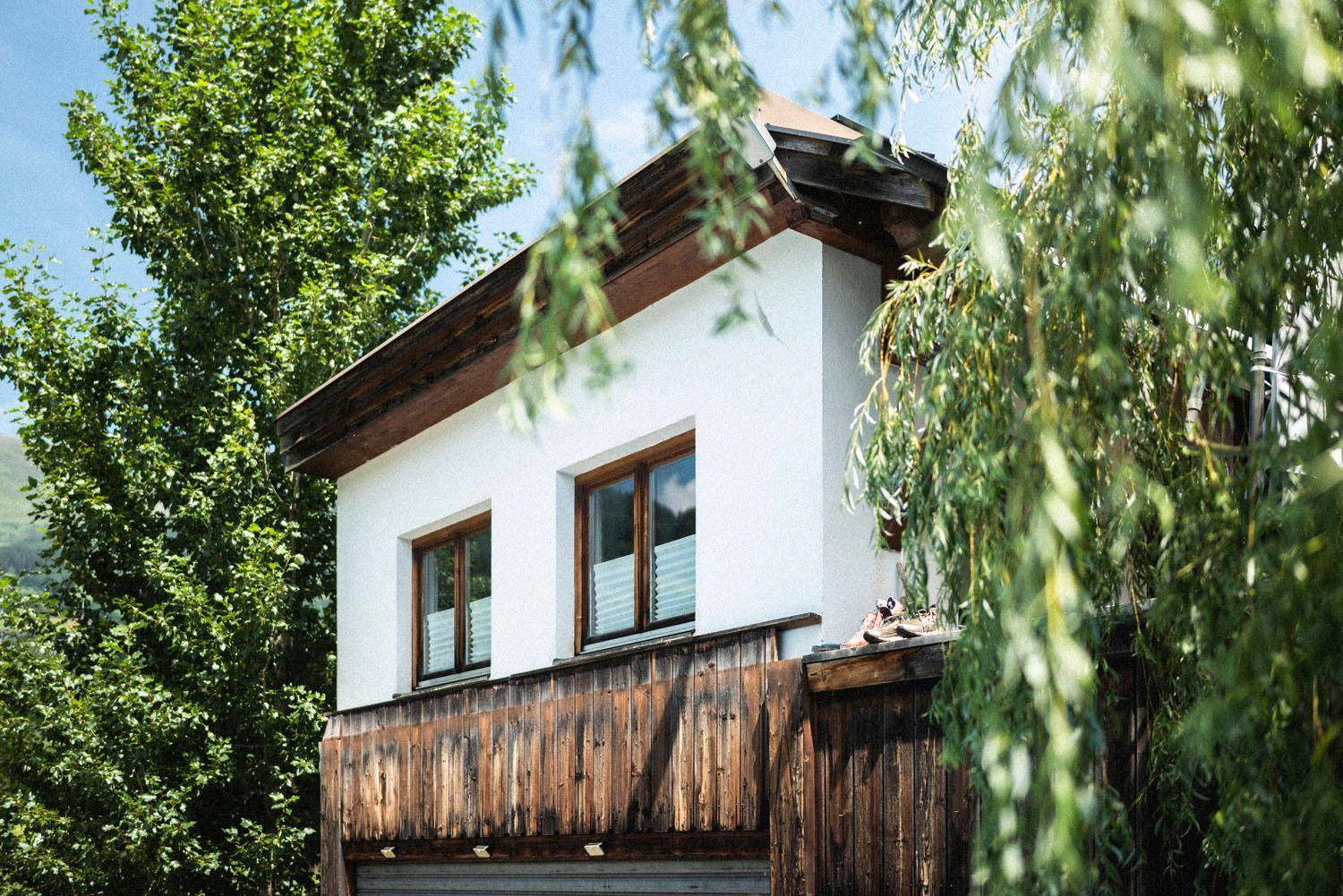 Fassade eines Gebäudes mit weißem Putz und Holzverkleidung unter einem Vordach.