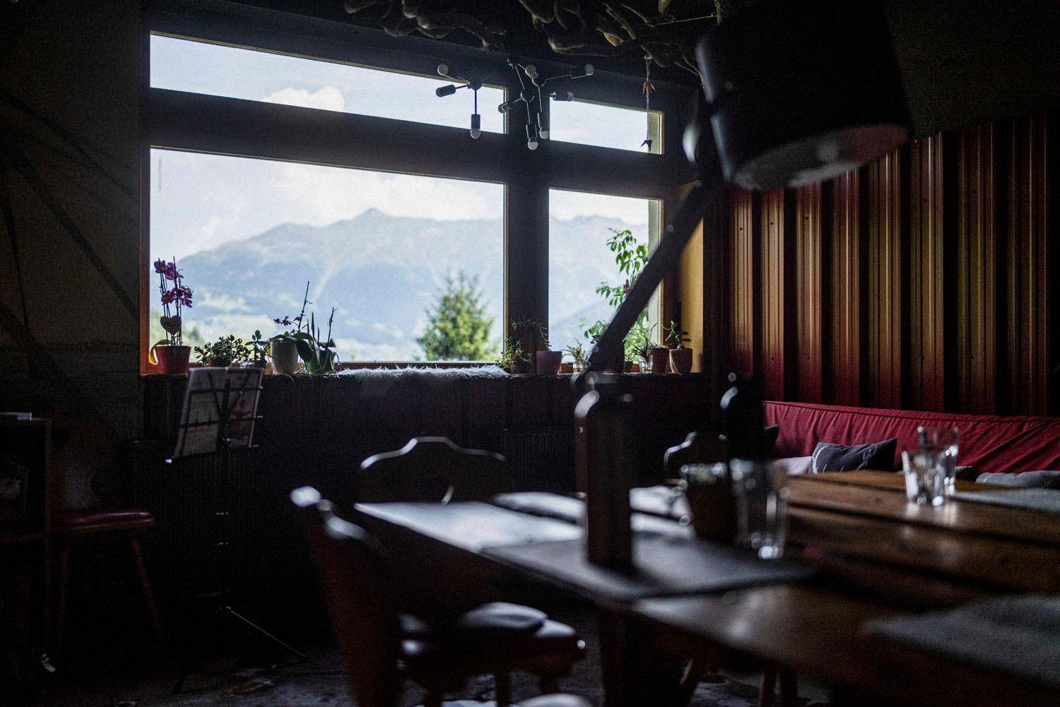 Gemütlicher Wohnbereich mit Bergblick durch große Fenster und rustikalen Möbeln.