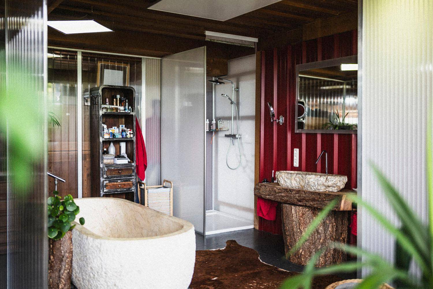 Geräumiges Badezimmer mit freistehender Steinbadewanne, Dusche und rustikalen Elementen.