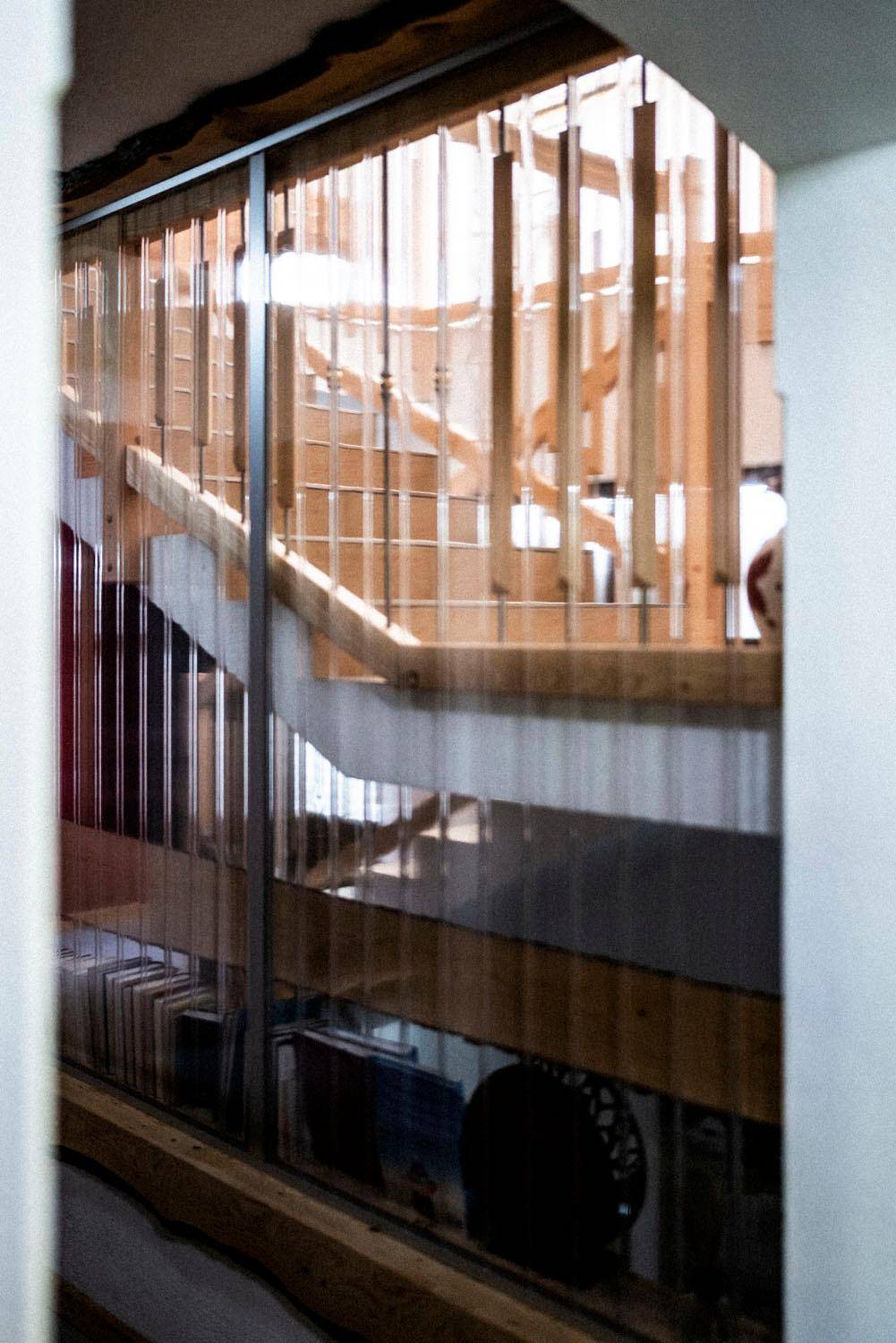 Modernes Treppenhaus mit Holzstufen und Glasabtrennung, das viel Licht durchlässt.