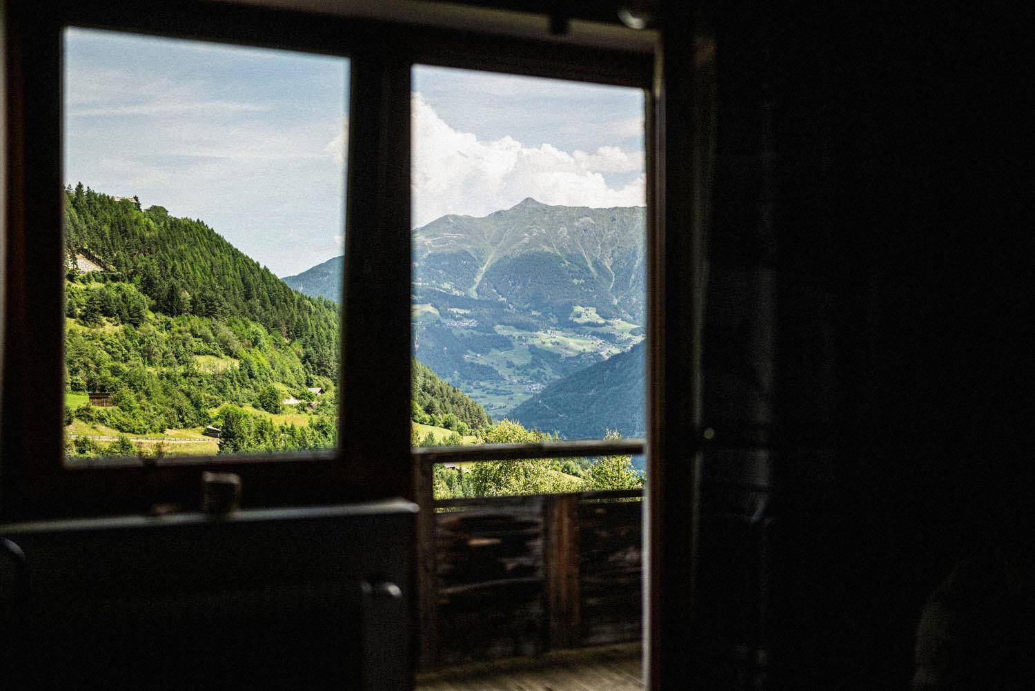 Heller Raum mit Zugang zu einem Balkon, der einen weiten Blick auf die grüne Berglandschaft bietet.