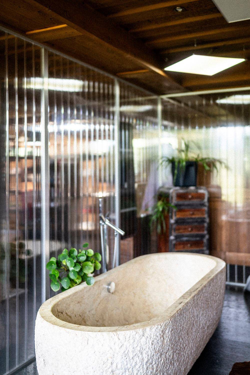 Modernes Badezimmer mit freistehender Steinbadewanne und Holzbalkendecke.
