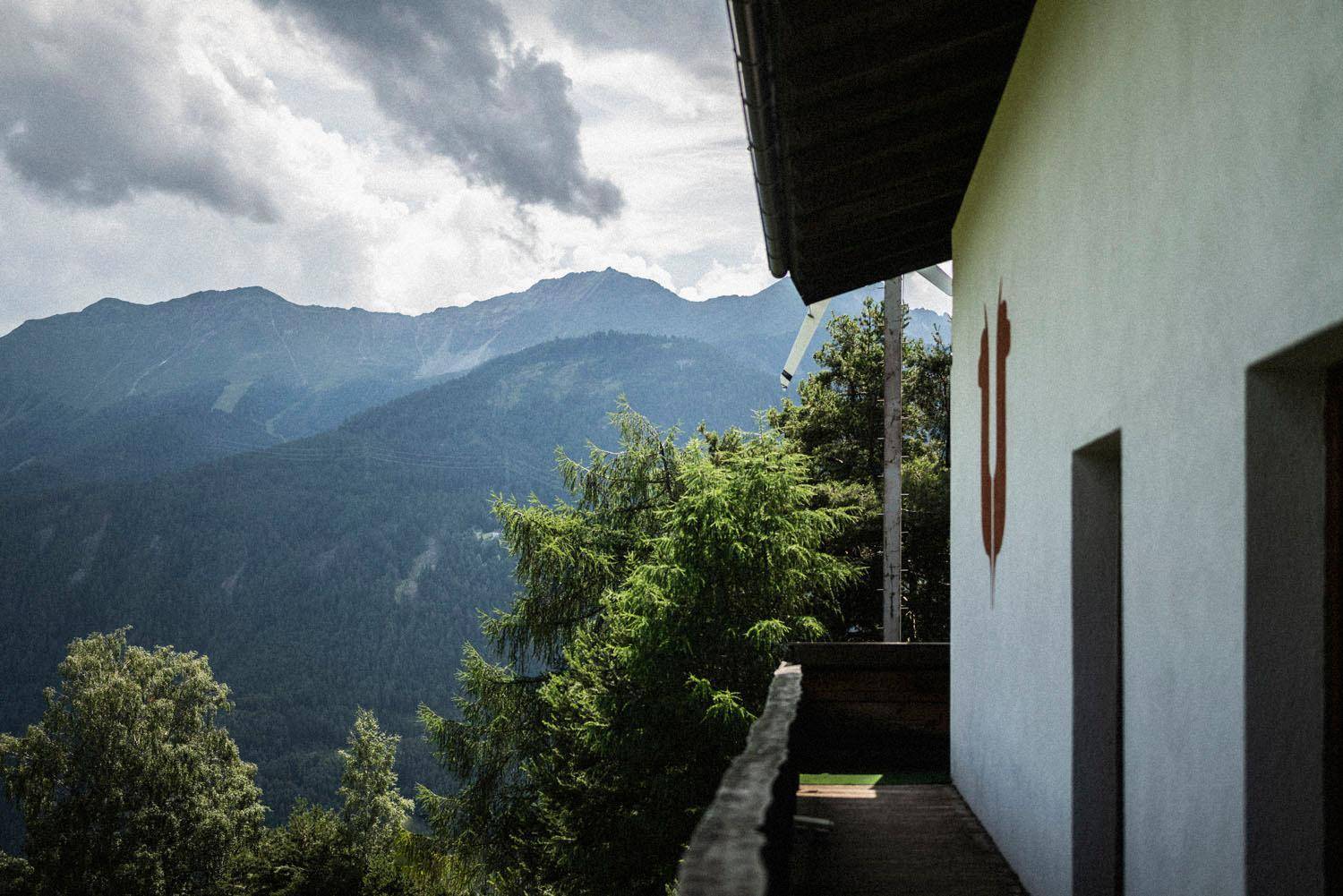 Seitenansicht des Hauses mit Balkon und einem weiten Blick auf die umliegende Berglandschaft.