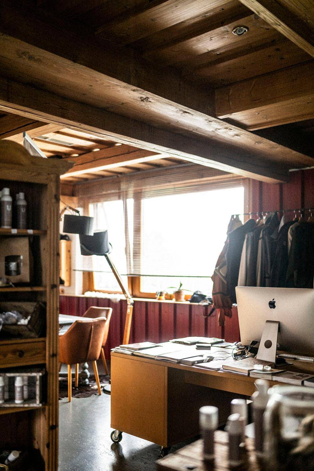 Rustikales Büro mit Holzbalkendecke, großem Fenster und modernem Computerarbeitsplatz.