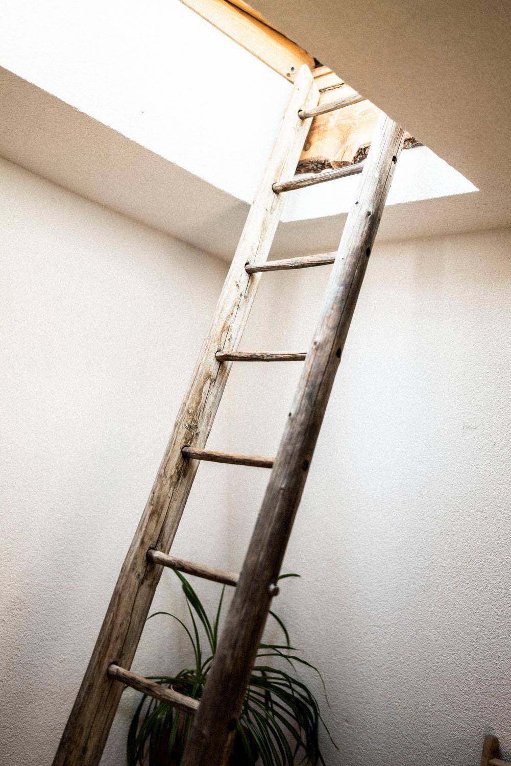 Rustikale Holzleiter führt zu einem Dachfenster, das viel natürliches Licht in den Raum bringt.