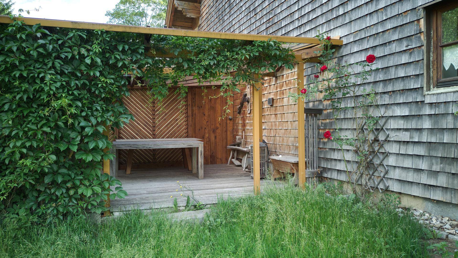 Rustikale Holzterrasse mit Pergola und üppigem Grün, ideal für entspannte Stunden im Freien.