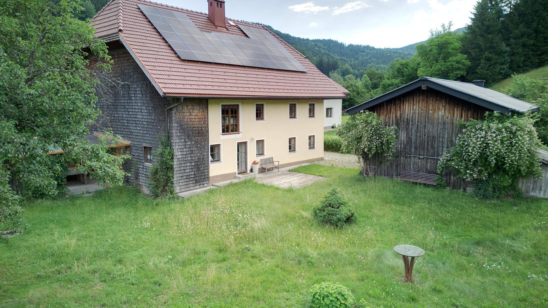 Ländliches Haus mit Photovoltaikanlage und großem Garten, umgeben von Natur.