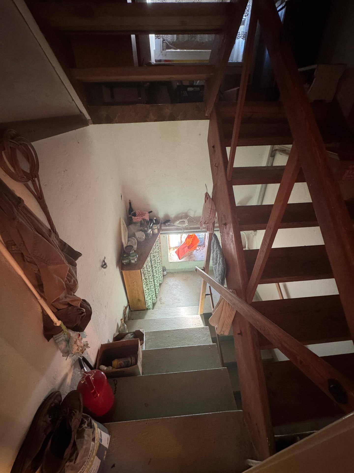 Holztreppe führt in ein Untergeschoss, mit sichtbaren Holzstufen und Geländer, einfach gehalten.