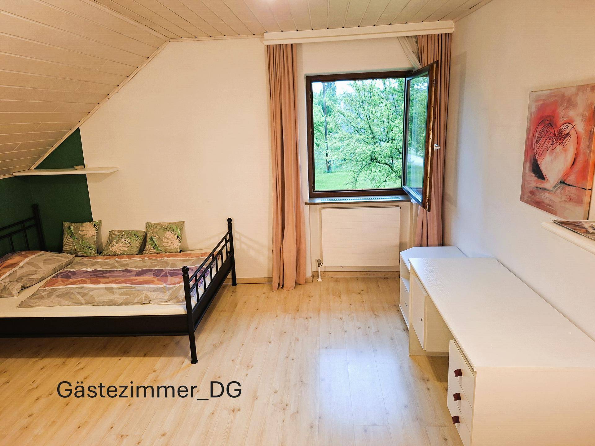 Gemütliches Gästezimmer im Dachgeschoss mit Einzelbett, Schreibtisch und Fenster mit Blick ins Grüne.