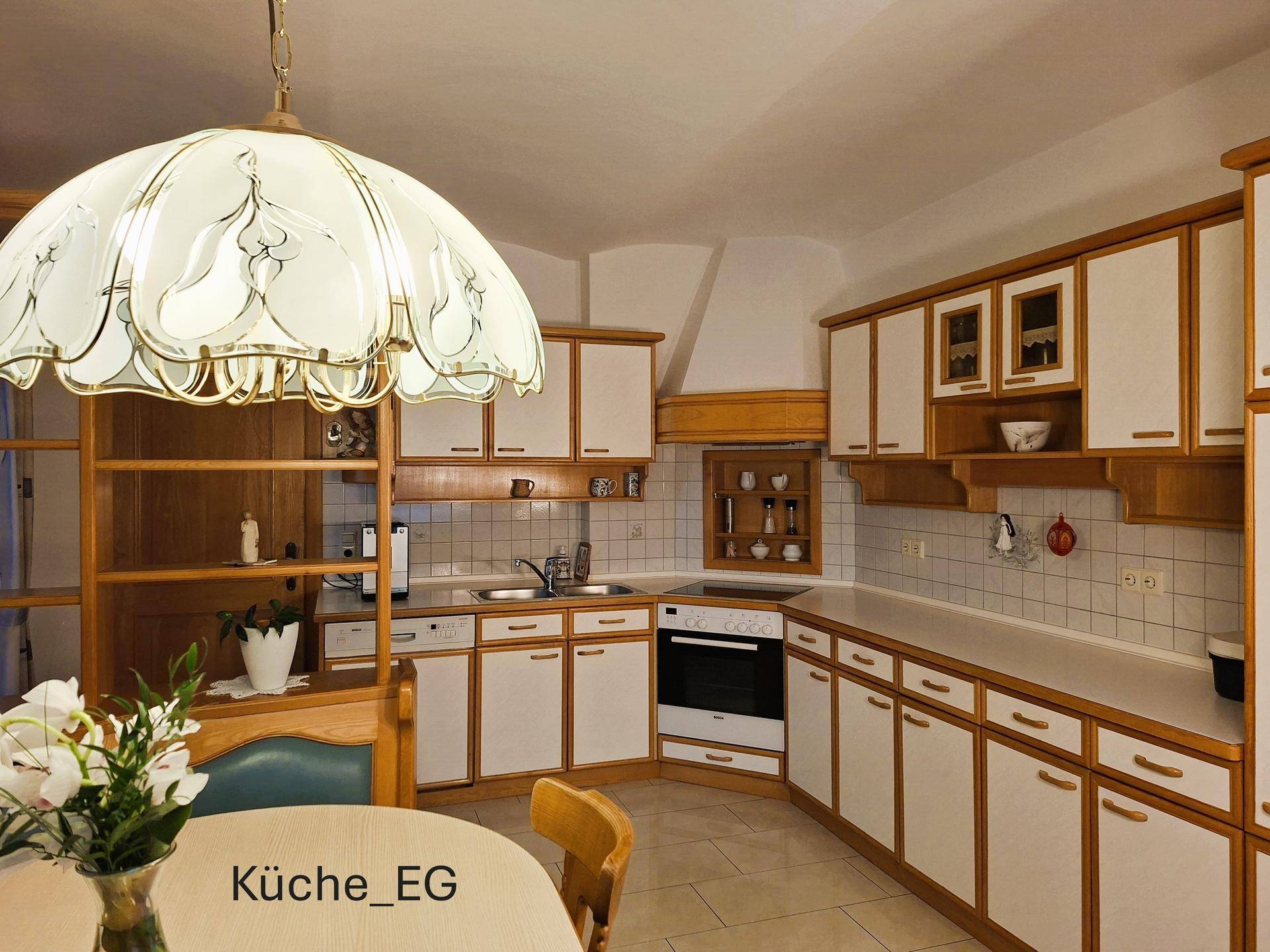 Traditionelle Einbauküche im Erdgeschoss mit hellen Fronten, Holzelementen und integriertem Essbereich.