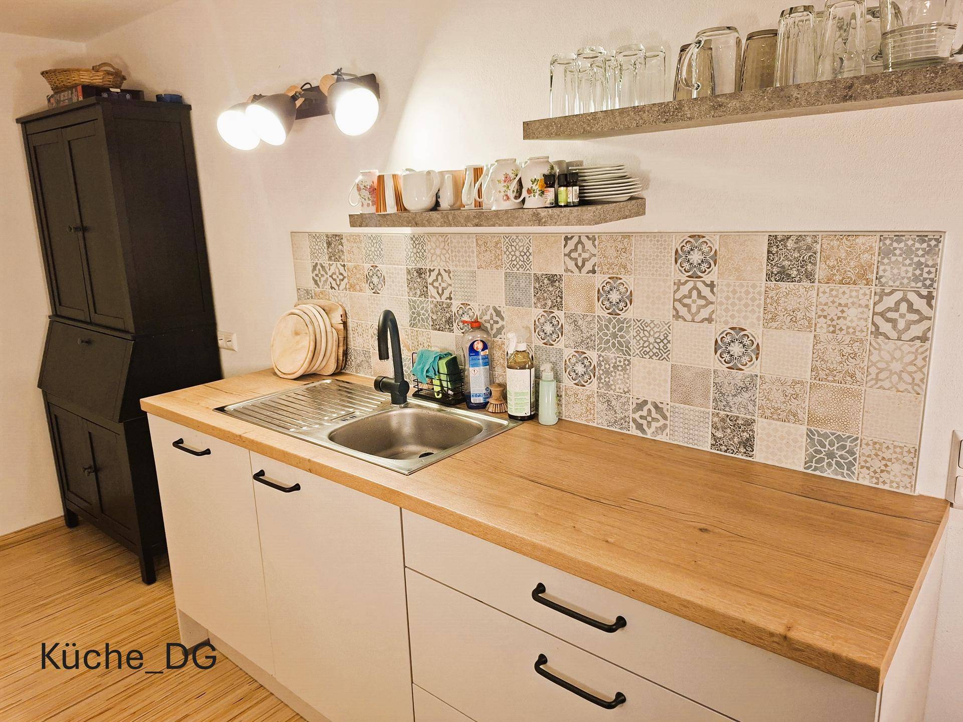 Moderne Küche im Dachgeschoss mit Spülbecken, Holzarbeitsplatte und gemusterten Fliesen als Spritzschutz.