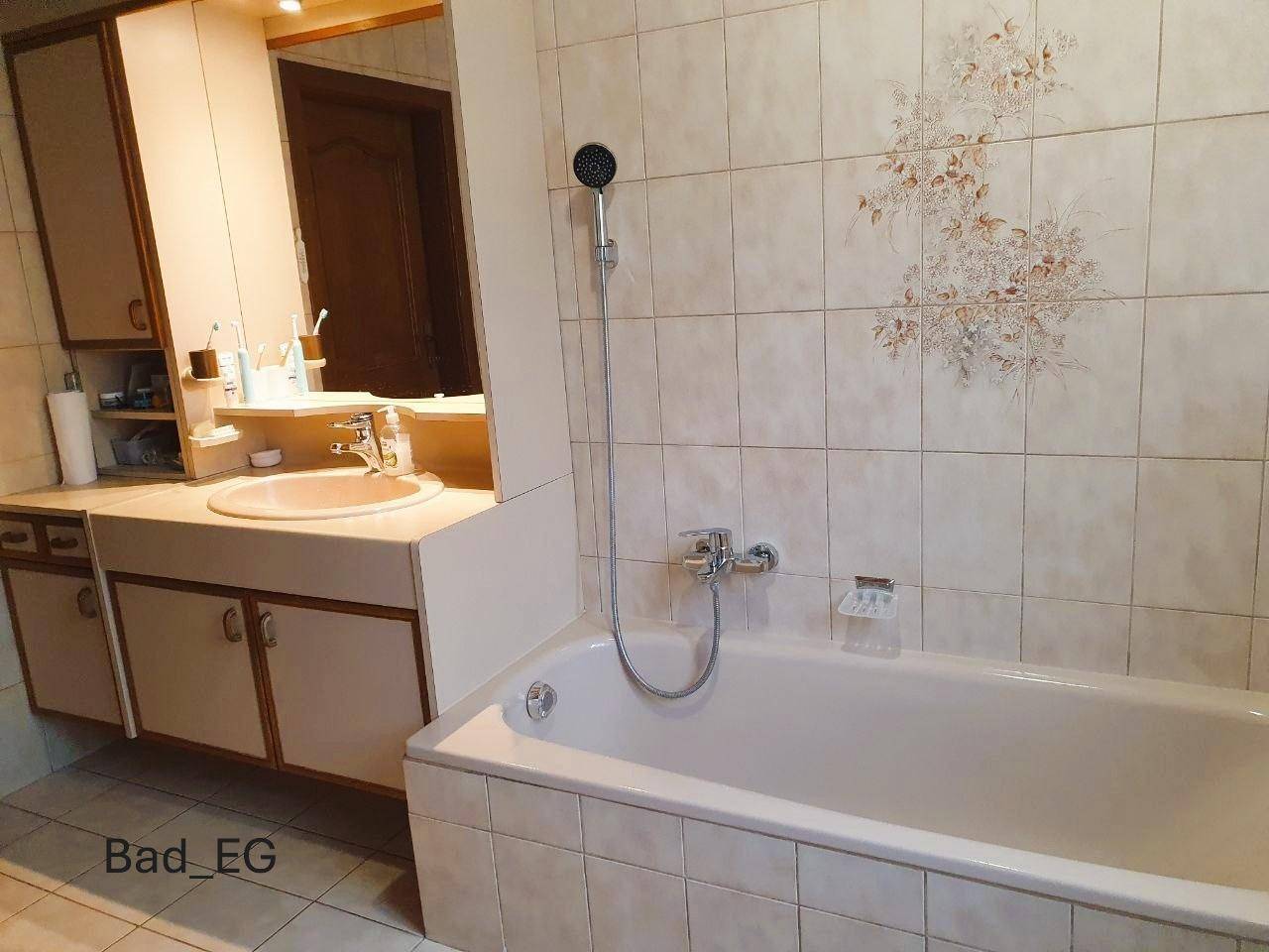 Badezimmer im Erdgeschoss mit Badewanne, Einzelwaschbecken und hellen Fliesen, funktional eingerichtet.