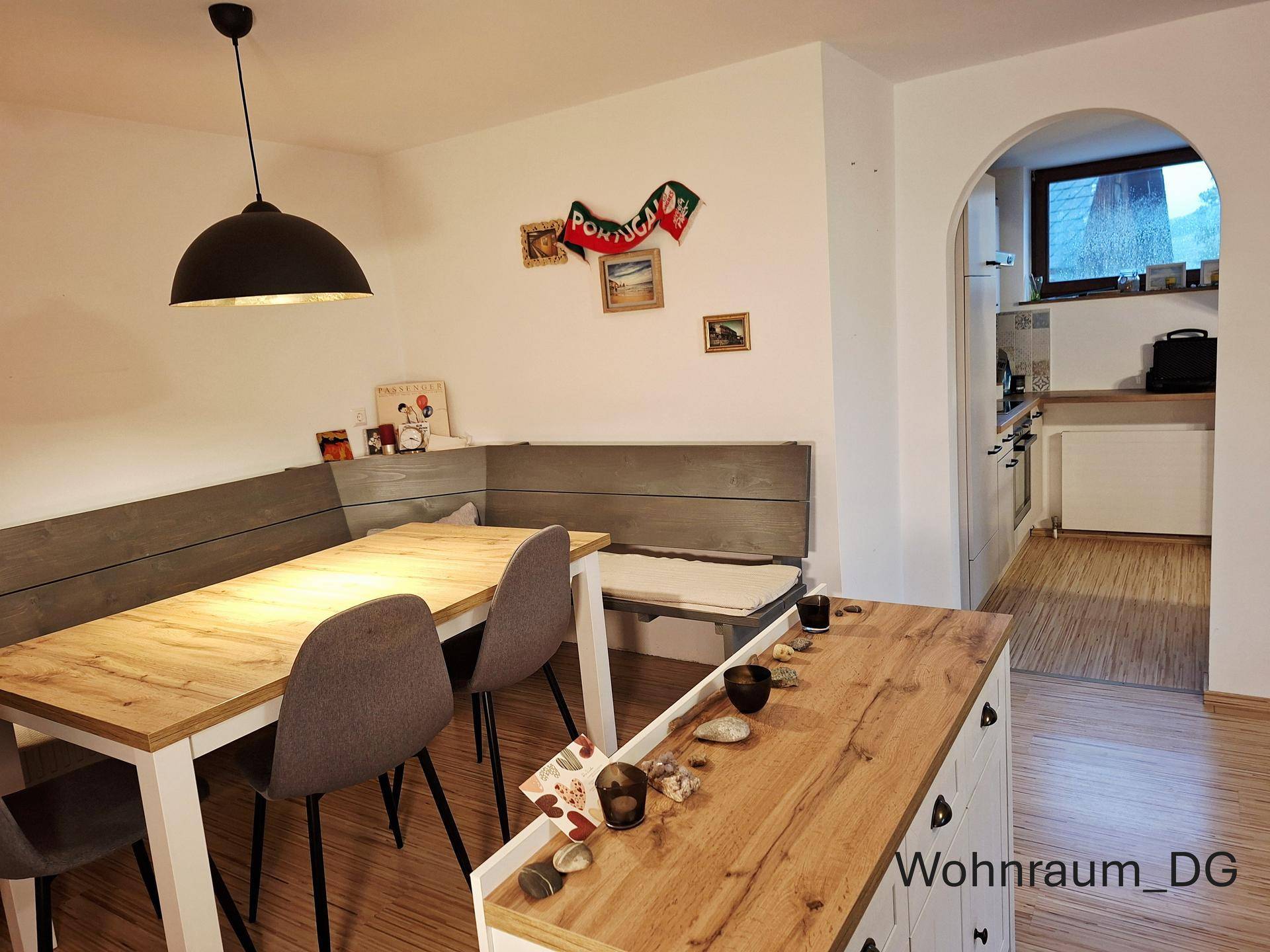 Essbereich im Dachgeschoss mit Holztisch und Sitzbank, offen gestaltet mit Durchgang zu weiterer Küche.