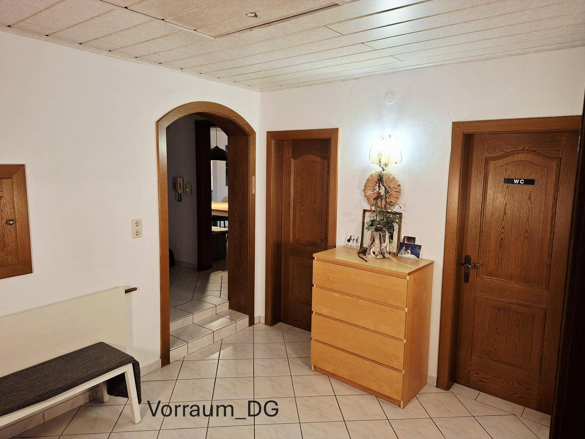 Heller Vorraum im Dachgeschoss mit Fliesenboden und Holztüren, schlicht und funktional gestaltet.