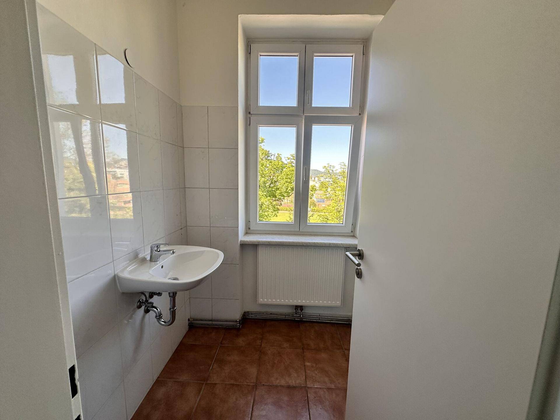 Kleiner Raum mit Waschbecken, Fenster und weißen Fliesen, ideal als Gäste-WC oder Hauswirtschaftsraum.