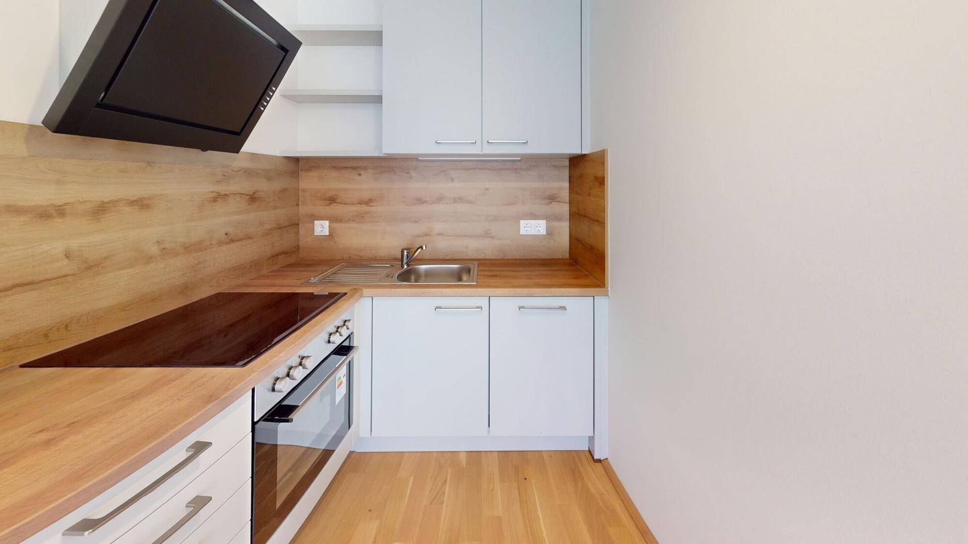 Moderne Einbauküche mit hellgrauen Schränken, Holz-Arbeitsplatten und integrierten Geräten.