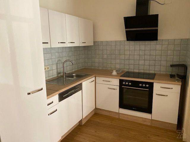 Weiße Einbauküche mit Holz-Arbeitsplatte, Fliesenrückwand und modernen Geräten.