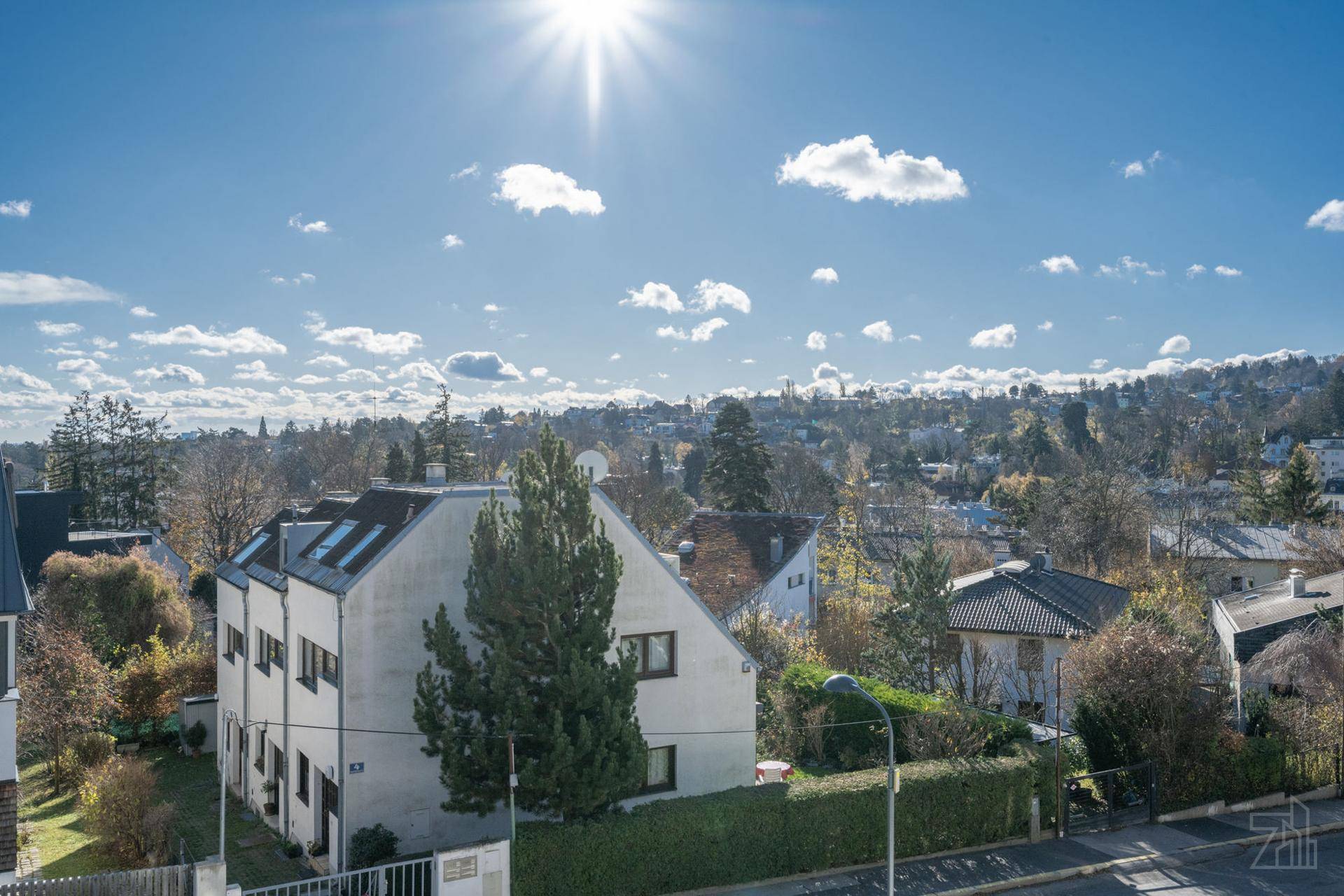 Weitläufiger Blick über die grüne Umgebung mit Wohngebäuden unter blauem Himmel.