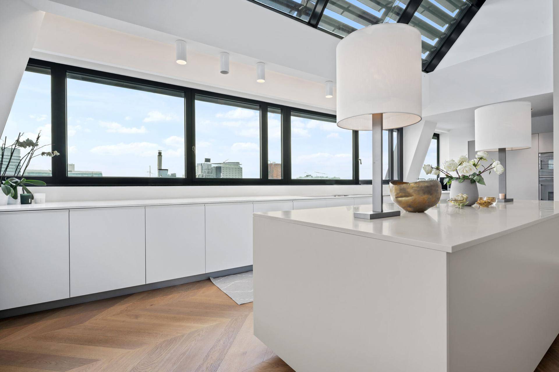 Moderne Küche mit weißer Kücheninsel, viel Stauraum und weitem Stadtblick.