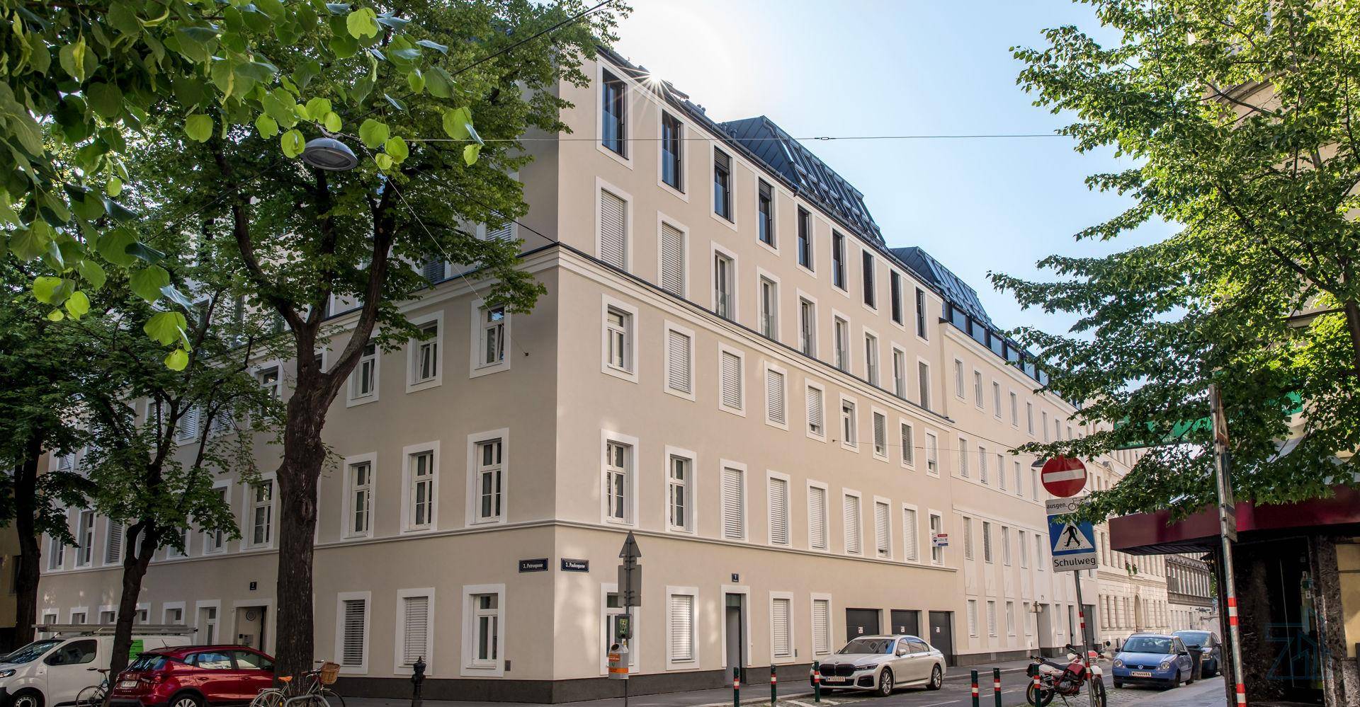 Mehrstöckiges Wohngebäude mit heller Fassade und vielen Fenstern in einer städtischen Umgebung.