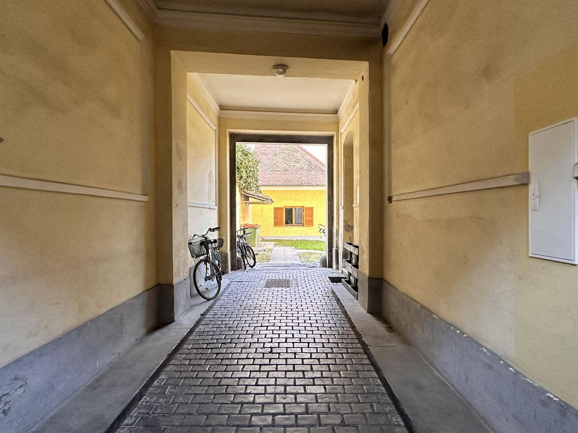 Historischer Durchgang mit Kopfsteinpflaster, der zu einem Innenhof führt.