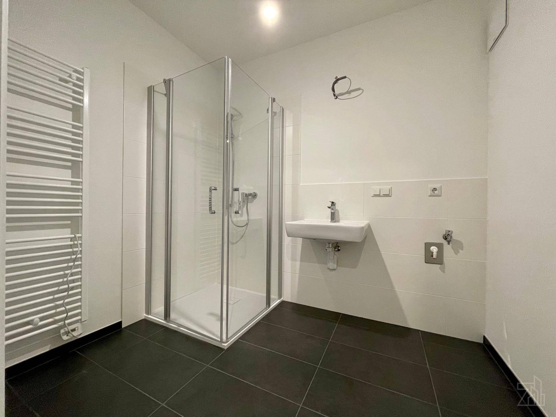 Modernes Badezimmer mit Duschkabine, Waschbecken und beheiztem Handtuchhalter.