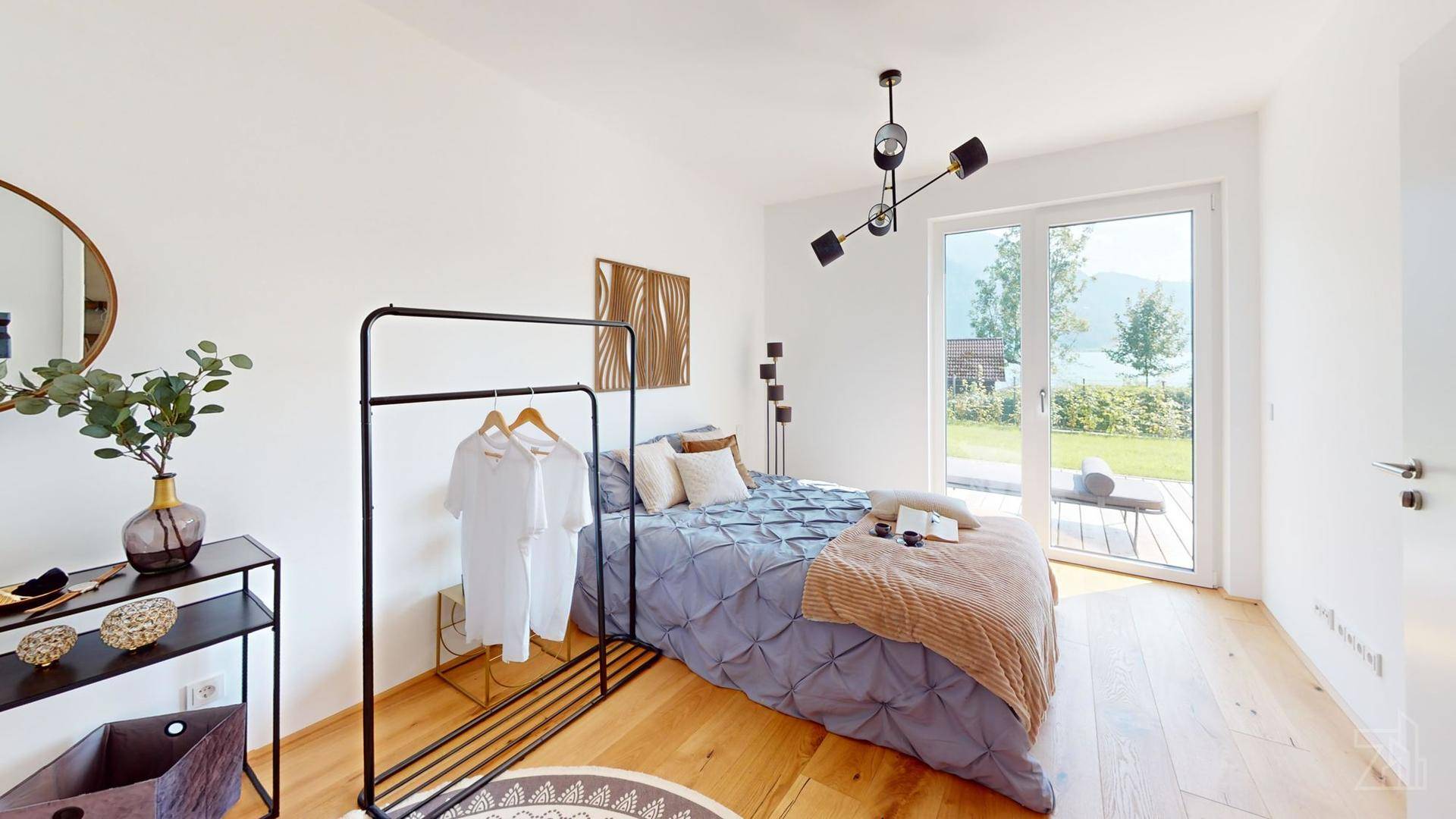 Helles Schlafzimmer mit Holzboden, Zugang zur Terrasse und Blick auf den See und die Berge.