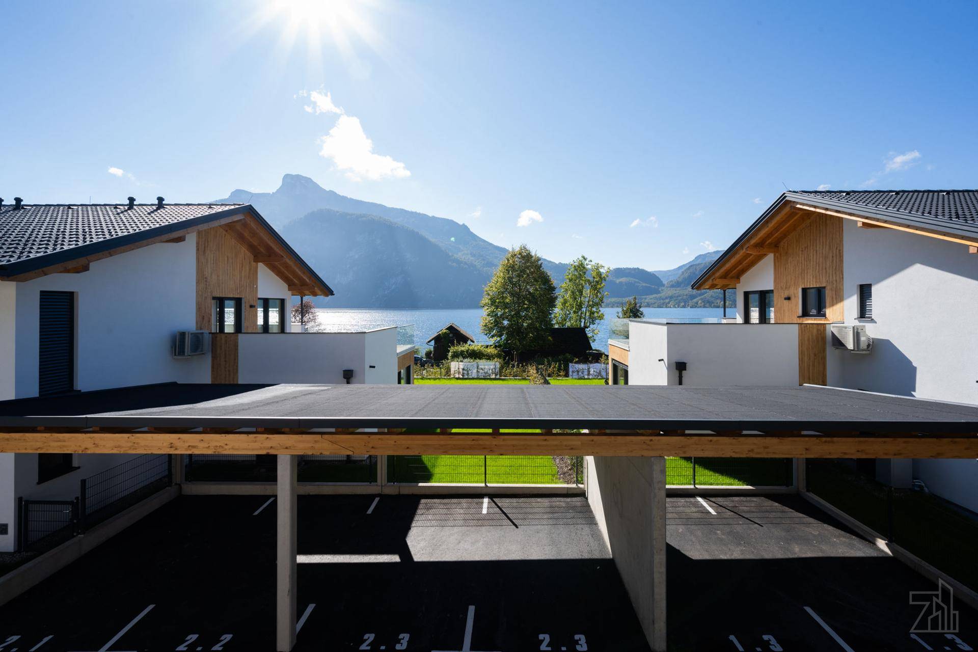 Moderne Häuser mit Carport und Blick auf den See sowie die umliegende Berglandschaft.