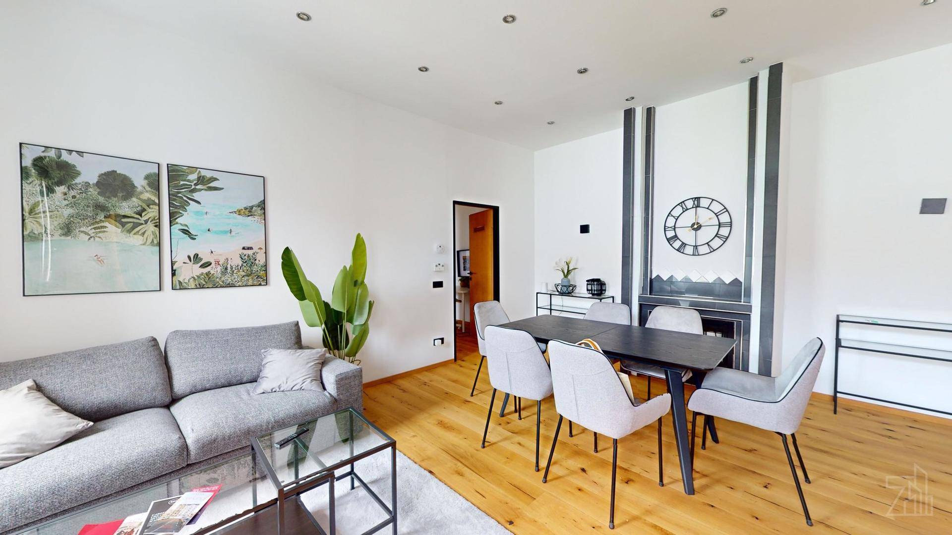 Offener Wohn- und Essbereich mit Holzboden, modernem Sofa und Esstisch.