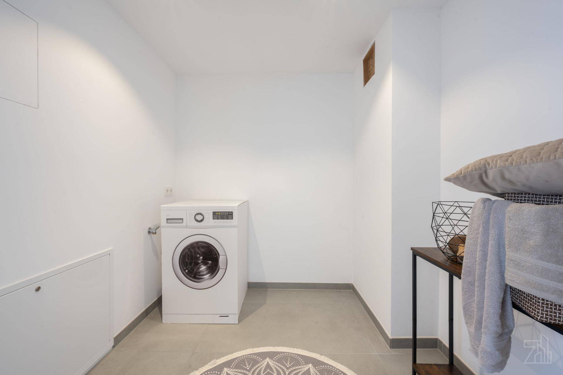 Praktischer Hauswirtschaftsraum mit Waschmaschine, Fliesenboden und ausreichend Platz.