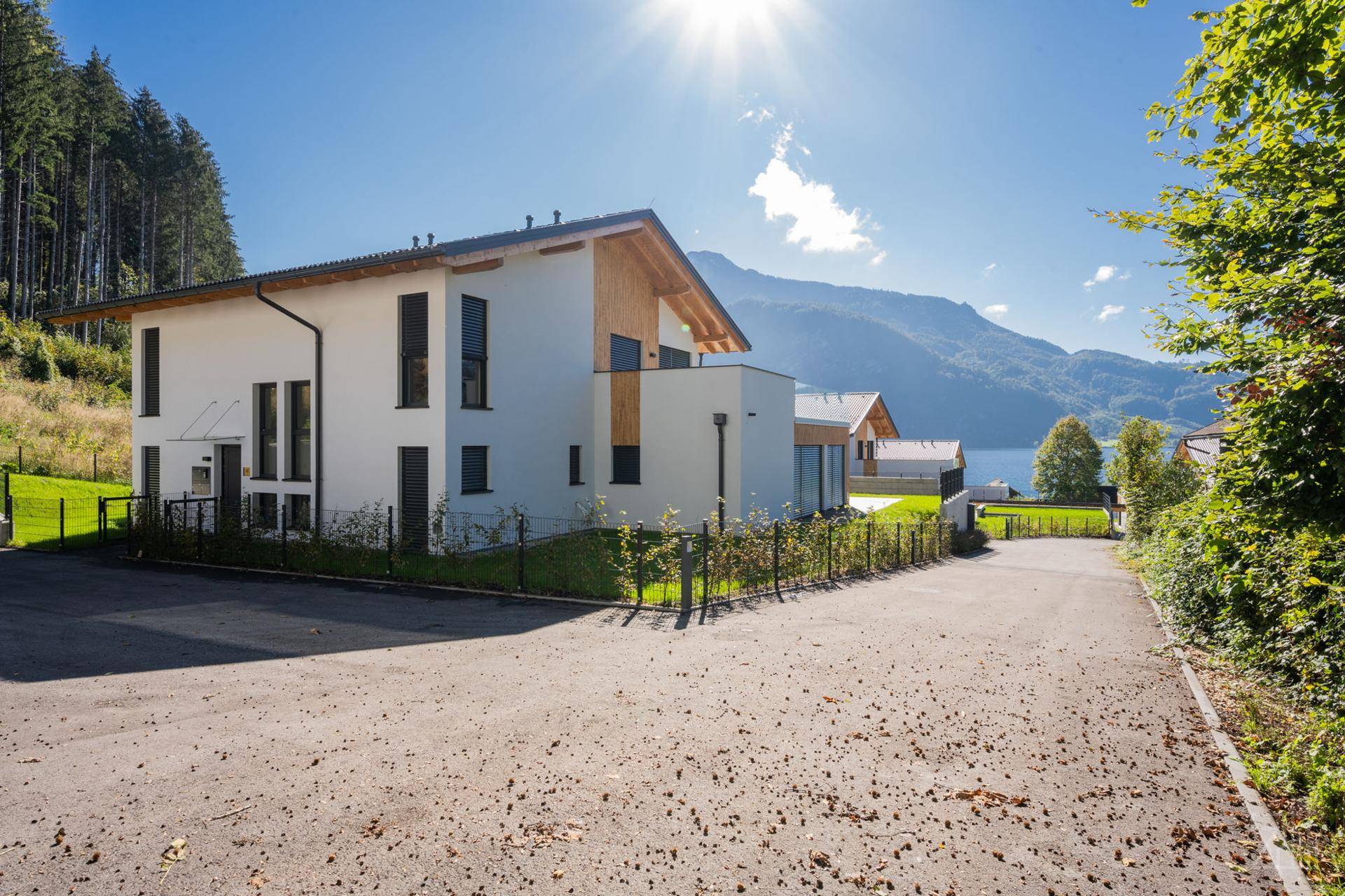 Moderne Architektur mit weißer Fassade, Holzdetails und Blick auf den See und die Berge.