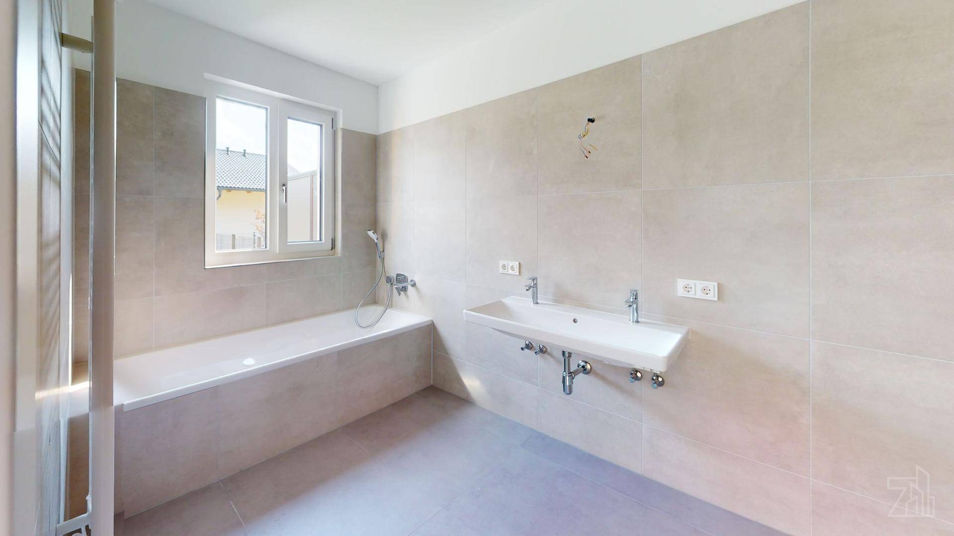 Modernes Badezimmer mit Badewanne, Einzelwaschbecken und hellen Fliesen, bereit zur Fertigstellung.
