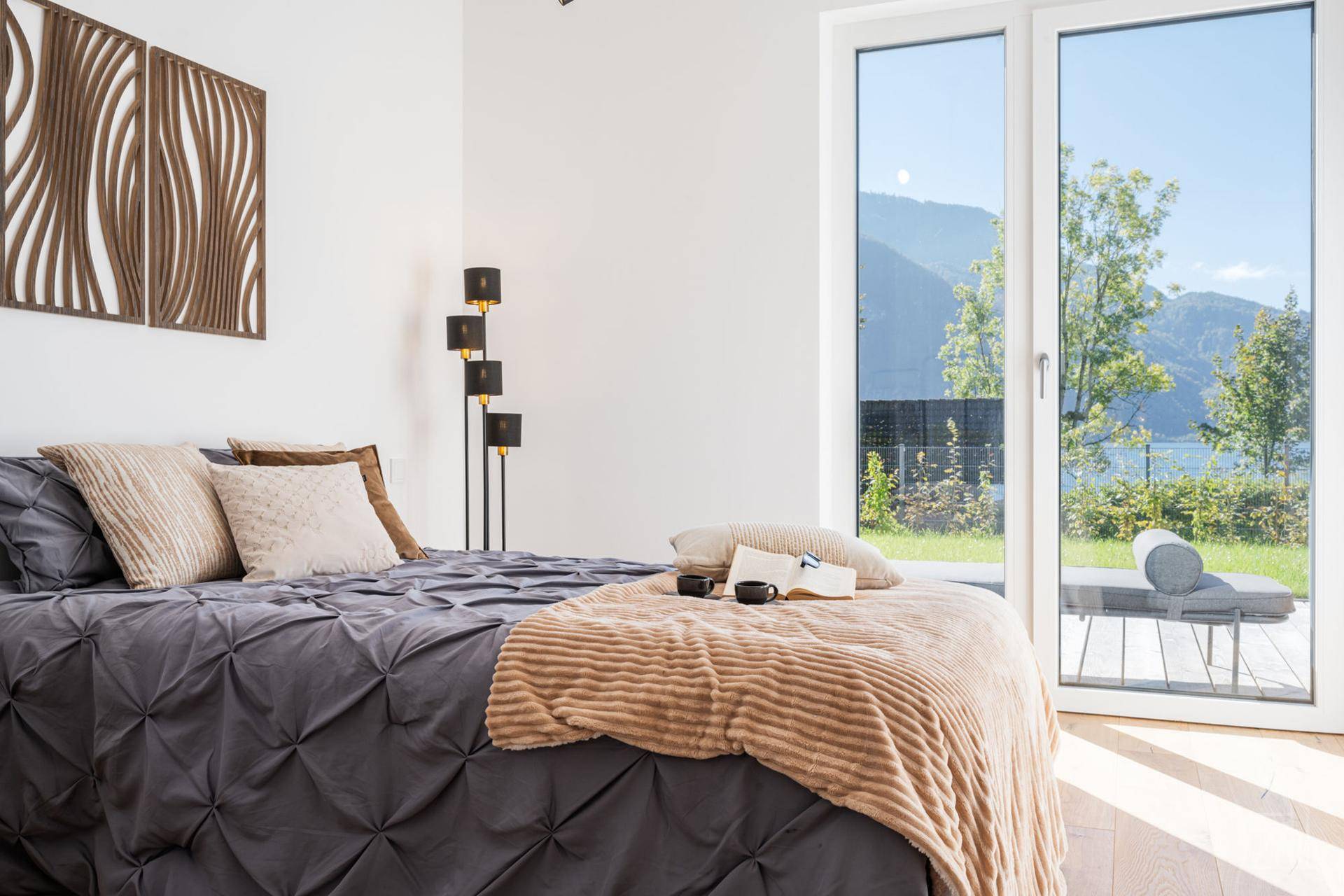 Gemütliches Schlafzimmer mit Seeblick, großen Fenstern und modernem Dekor, ideal zum Entspannen.